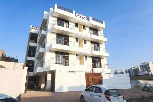 a white building with a car parked in front of it at OYO Flagship 61722 Rajmahal Residency Hotel in Bhiwadi