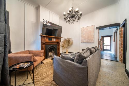 a living room with two couches and a fireplace at Blacksmith Cottage Aldinga in Aldinga