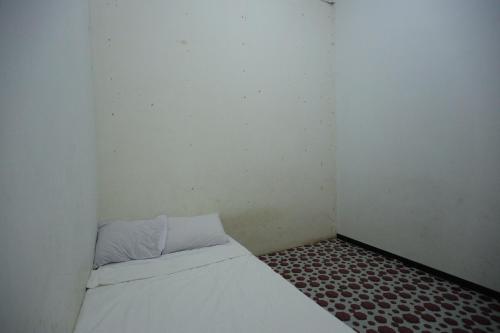 巴淡島中心的住宿－SPOT ON 93446 Penginapan Mak Yes，一间白色的小房间,里面设有一张床