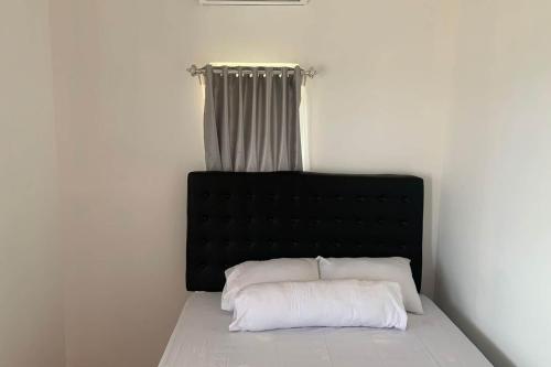 1 cama con cabecero negro y 2 almohadas blancas en Capital O 93437 Embung Banteran Cottage, en Banyumas