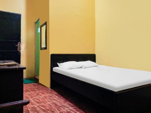a bed in a room with yellow walls at OYO 93443 Emmy Homestay Syariah in Mamuju