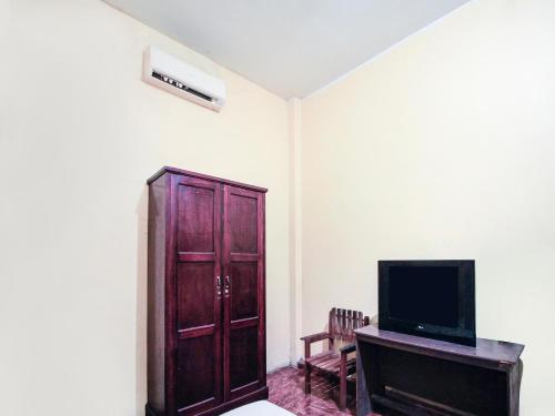 a living room with a tv and a wooden cabinet at OYO 93443 Emmy Homestay Syariah in Mamuju