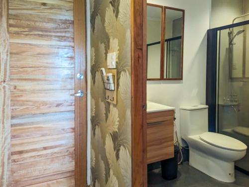 a bathroom with a toilet and a wooden door at Ponderosa Golf and Resort in Puerto Galera