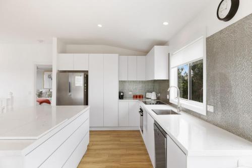 a white kitchen with white cabinets and a window at Peppermint Lookout in Kilcunda