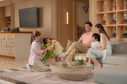 a family sitting on a couch in a living room at Novotel Living Bangkok Sukhumvit Legacy in Bangkok