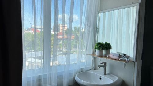 ein Badezimmer mit einem Waschbecken und einem großen Fenster in der Unterkunft Muji Hotel KrabI in Krabi