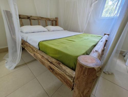 a bedroom with a wooden bed with a green blanket at Vacation Home with Lake view in Kampala