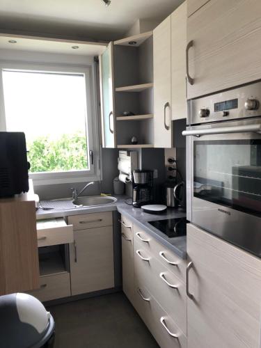 une cuisine avec des armoires blanches et une fenêtre dans l'établissement T2 lumineux avec balcon et parking, à Bagnoles-de-l'Orne