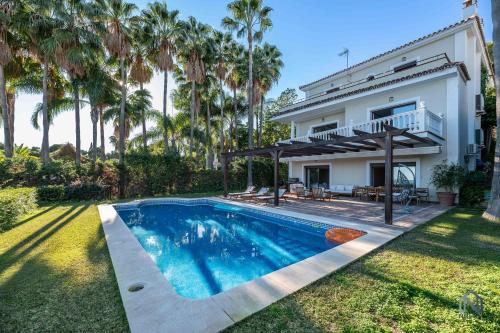 uma piscina em frente a uma casa com palmeiras em Spacious 6 BDRM Villa - Golf Lover's Paradise em Marbella