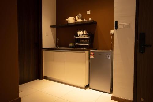 a small kitchen with a refrigerator and a shelf at K Avenue by Pinstay in Donggongon