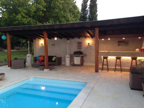 une terrasse avec une piscine et une pergola en bois dans l'établissement Villa, à Agonges