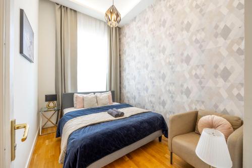 ein Schlafzimmer mit einem Bett und einem Stuhl in der Unterkunft Luxury Quentin Apartment 3 BEDRM, 2 BATHRM in Budapest