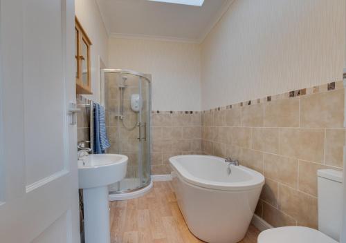 a bathroom with a tub and a sink and a toilet at Mews Cottage in Scarborough