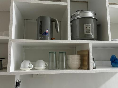 a kitchen cabinet with dishes and appliances in it at Condotel - Minimalistic 2 minutes walk to SM Marilao in Marilao