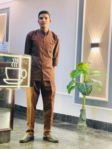a man standing next to a vase with a plant at HOTEL ROYAL PRESIDENCY INN in Lucknow