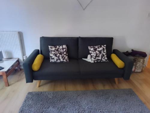 um sofá preto com almofadas numa sala de estar em Lodgings. em Londres