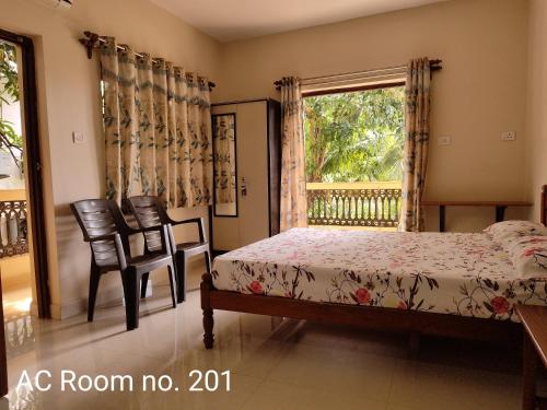 a bedroom with a bed and two chairs and a window at Indraprasth Palolem Hill in Palolem
