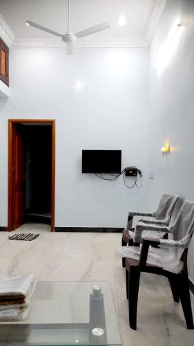 a white room with a chair and a tv on a wall at adhirai's home stay in Pondicherry