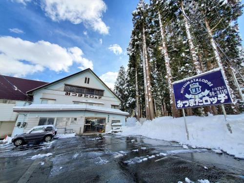 a sign in the snow in front of a building at みつまたロッヂ in Yuzawa