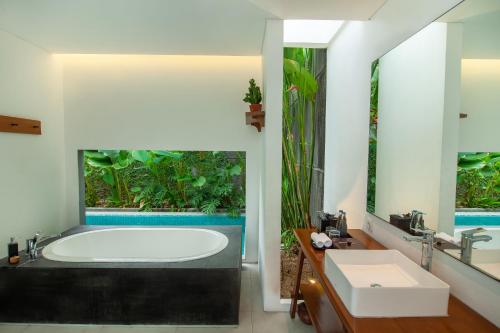 a bathroom with a tub and a large window at Abia Villas in Legian