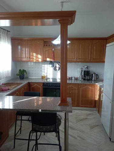 a kitchen with wooden cabinets and a table with chairs at Άνετο εξοχικό με ιδιωτικό χώρο στάθμευσης in Astrítsa