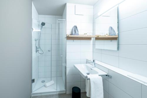 a white bathroom with a sink and a shower at Hotel Berghof in Petersberg