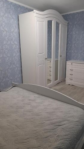 1 dormitorio con espejo, 1 cama y vestidor en Двухкомнатная в 4 микрорайоне, en Uralsk