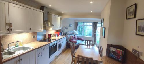 cocina con armarios blancos, mesa y fregadero en Shear Annexe Flat en Cambridge