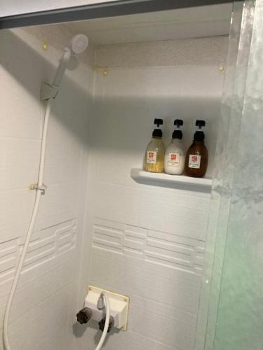 La salle de bains est pourvue d'une douche et de 4 bouteilles de savon. dans l'établissement 海空リゾートうみのいえ, à Yomitan