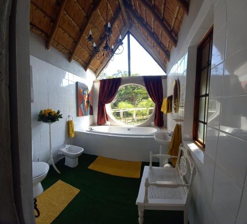 baño con bañera, aseo y ventana en Ascot Bush Lodge, en Pietermaritzburg