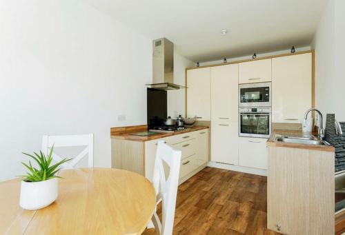 a kitchen with white cabinets and a wooden table at Modern 4 bed house perfect for contractors with free parking in Manchester