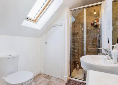 y baño con ducha, aseo y lavamanos. en Modern 4 bed house perfect for contractors with free parking, en Mánchester