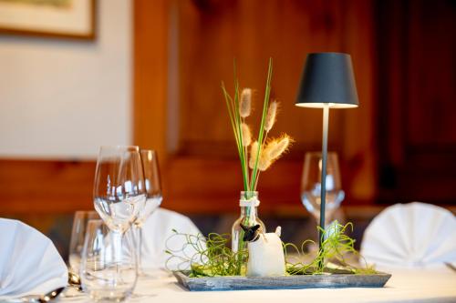 a table with a lamp and wine glasses on it at Hotel Berghof in Petersberg