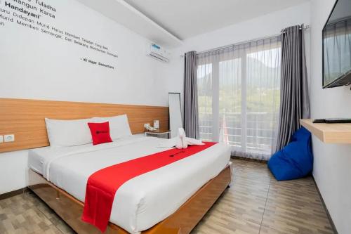 a bedroom with a large bed and a large window at RedDoorz near Jawa Timur Park 2 in Malang