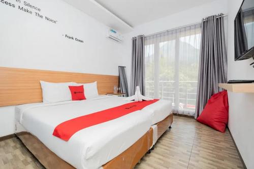 a bedroom with a large bed and a large window at RedDoorz near Jawa Timur Park 2 in Malang