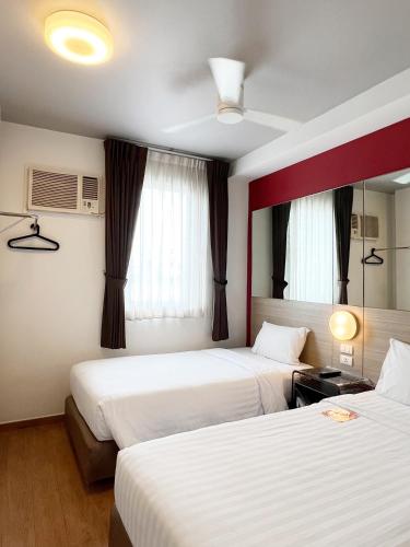 a hotel room with two beds and two windows at Easy Planet Pattaya in Pattaya