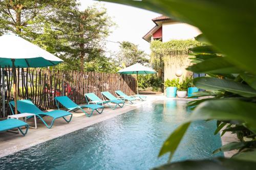 a swimming pool with blue chairs and umbrellas at Wasabi in Canggu