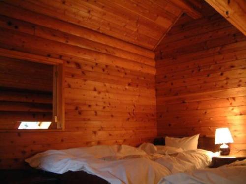 a bedroom with a wooden wall with two beds at Mori no Kuni - Vacation STAY 03957v in Ōma