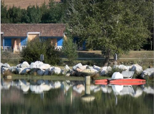 a red boat sitting in the water next to a house at Charmante maison dans le Gers, proche lac et centre-ville in LʼIsle-Jourdain