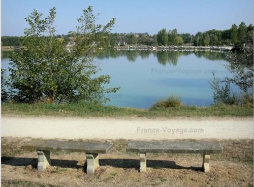 um banco sentado em frente a um lago em Charmante maison rénovée, proche lac et centre-ville em LʼIsle-Jourdain