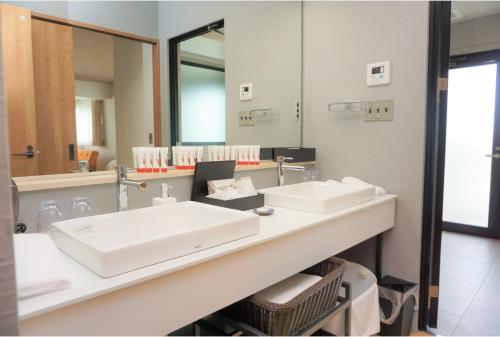 a bathroom with two sinks and a large mirror at ゆくれば前島ホテル in Naha