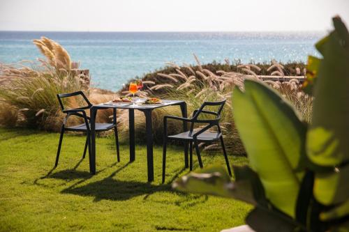 a table with two chairs and a glass of wine at Eden Beachfront Residences & Suites in Kastraki Naxou