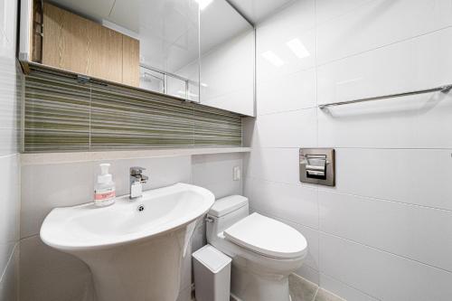 a white bathroom with a toilet and a sink at Urbanstay Myeongdong in Seoul