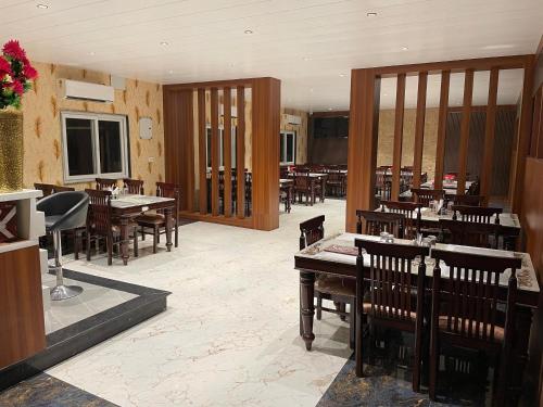 een restaurant met houten tafels en stoelen in een kamer bij THE SKYLITE HOTEL & BANQUET in Ara