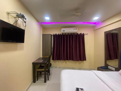 Pokój z łóżkiem, biurkiem i telewizorem w obiekcie Hotel Royal Grand - Near Mumbai International Airport w Bombaju