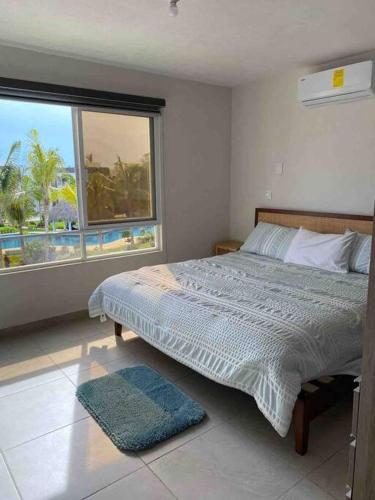 a bedroom with a bed and a large window at Hermoso Apartamento con club de playa in Acapulco