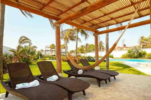a group of chairs sitting under a wooden pergola at Hermoso Apartamento con club de playa in Acapulco