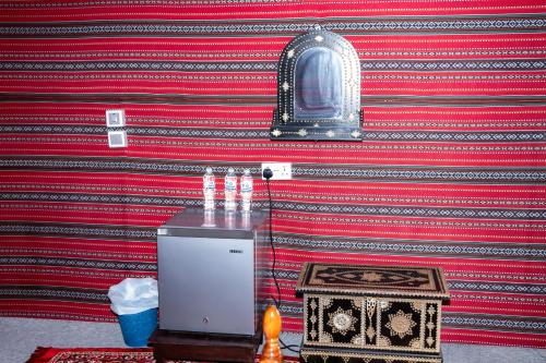 a red and black wall with a small refrigerator at Sand Delight Camp in Al Wāşil