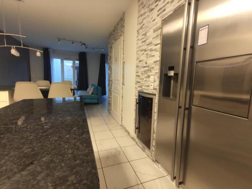 Il comprend une cuisine équipée d'un réfrigérateur en acier inoxydable et une salle à manger. dans l'établissement Serenity House - Geneva Luxe Calm Confort 8 pers - Viadora, à Beaumont