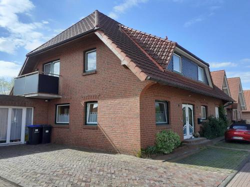 a red brick house with a roof at Balkonwohnung Leuchtturm in Hooksiel